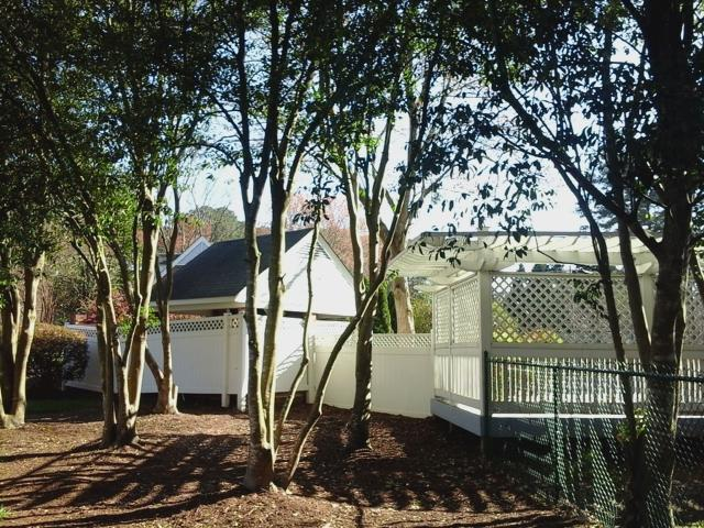 Trees surrounding a gazebo and shed in a landscaped yard, highlighting the importance of tree care for property aesthetics and safety.